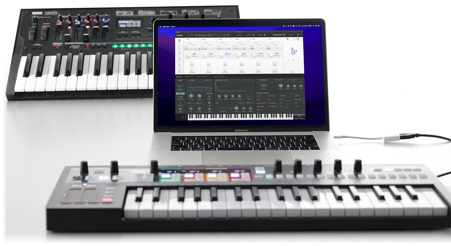 Un soberbio conjunto de tecnología sonora compuesto de Korg opsix native en un MacBook, sobre la imagen del hardware anterior opsix con teclado, y el maravilloso teclado MIDI avanzado KeyStep Pro de Arturia